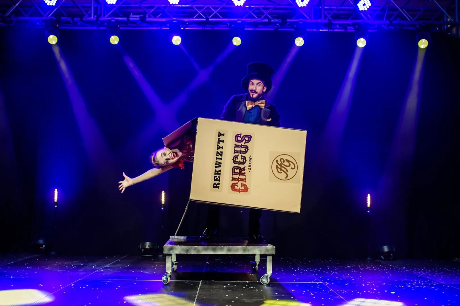 Pani Czarująca wyłania się ze skrzyni Circus SHOW w niebieskim świetle